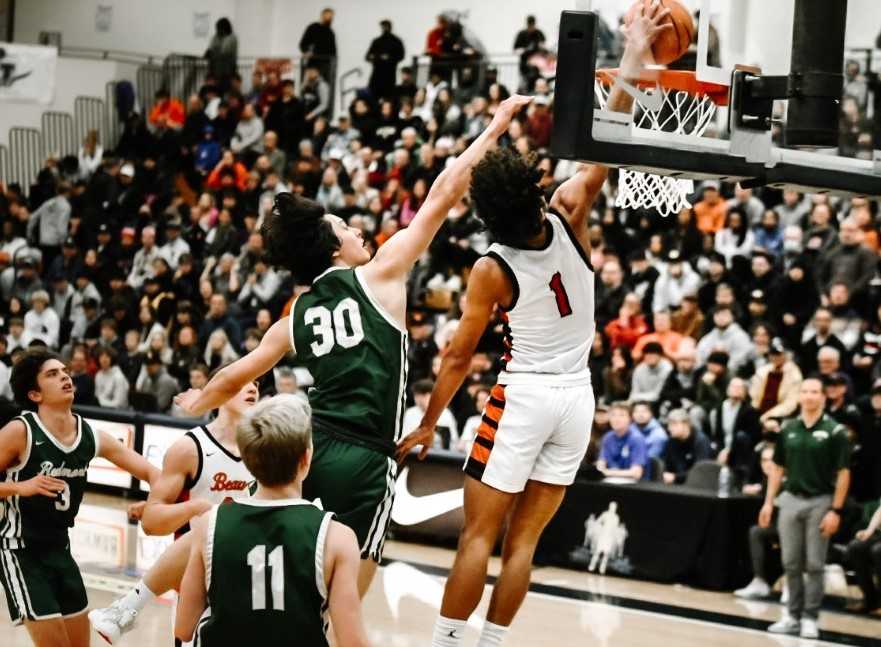 Beaverton's Jalen Childs (1) soars over Redmond's Josh Roof (30) in Tuesday's win at the LSI. (Photo by Fanta Mithmeuangneua)