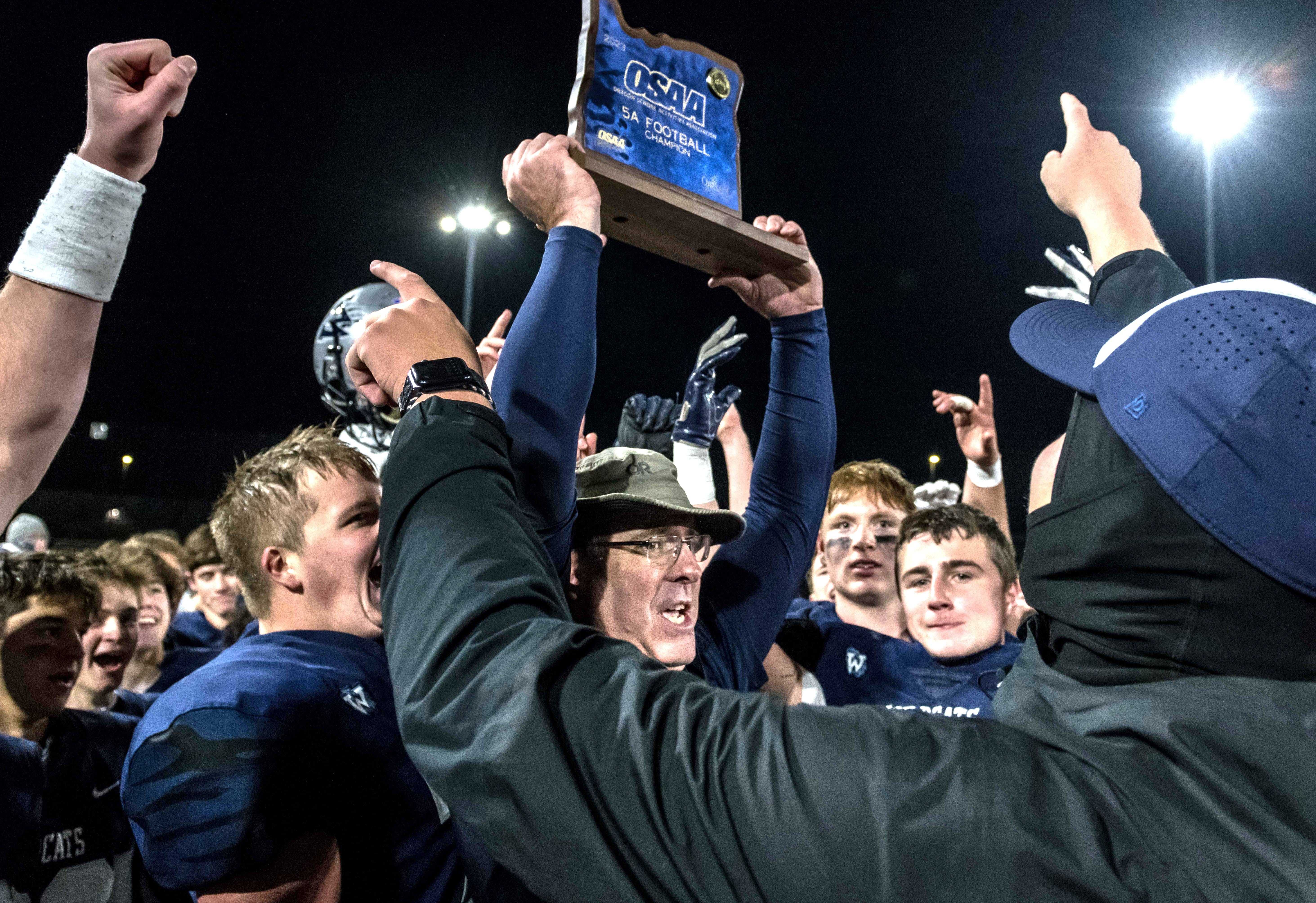 Wilsonville coach Adam Guenther and his players revel in claiming the 5A championship trophy Friday. (Photo by Greg Artman)