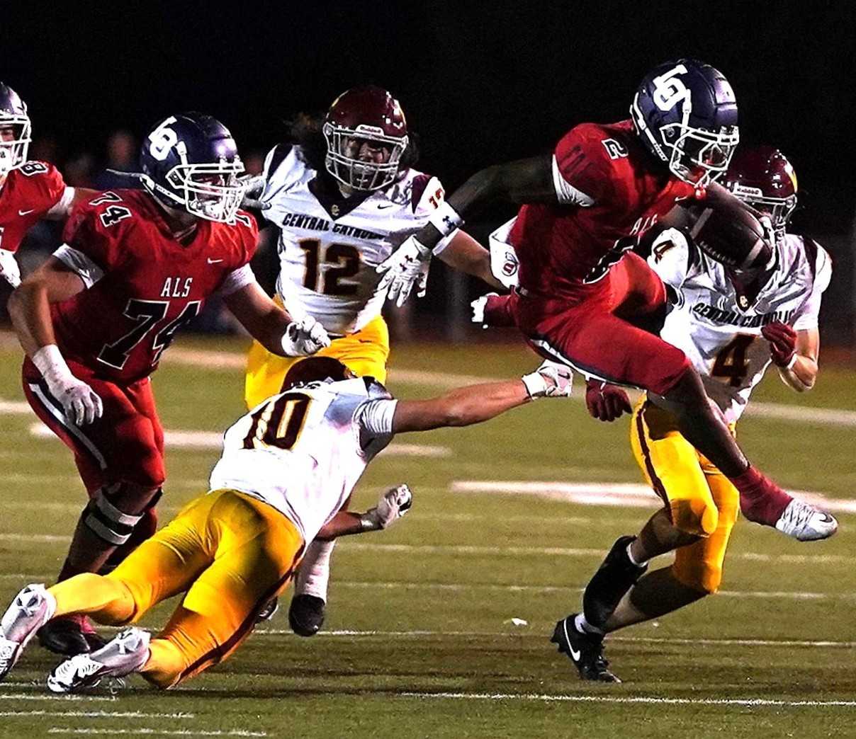 Lake Oswego's LaMarcus Bell hurdles past Central Catholic's Asa Lundberg (10) in Friday's nonleague game. (Photo by J.R. Olson)